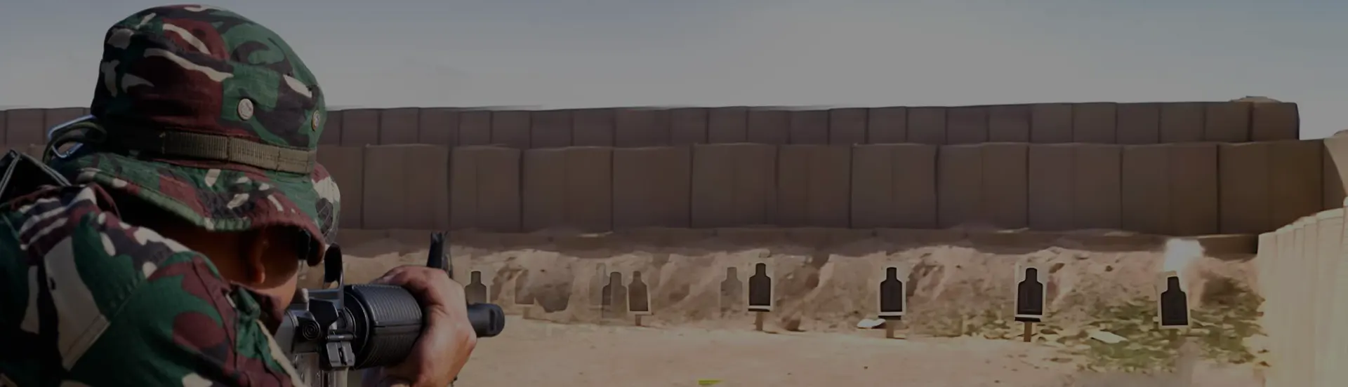Outdoor live-fire range with a shooter, target line and filled protective barrier structures